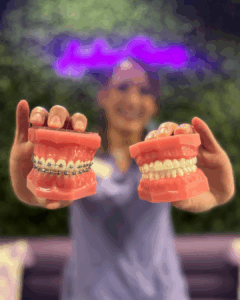 Megan, our treatment coordinator, is holding up two typodonts, one with braces on, and one with clear aligners on
